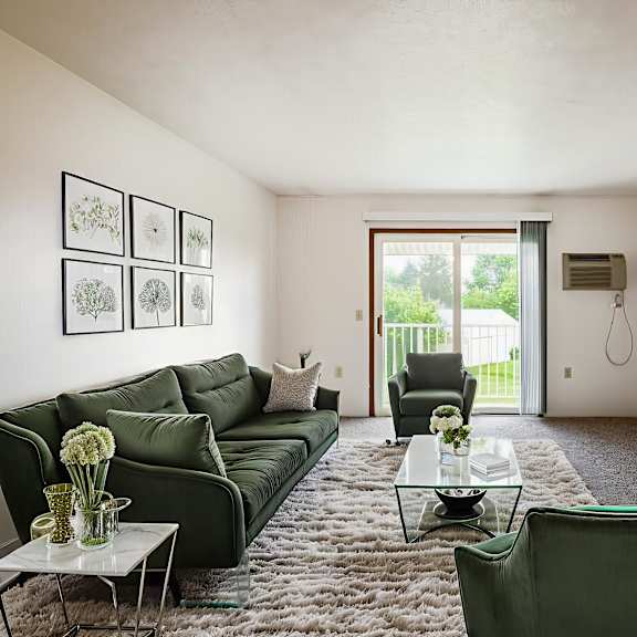 a living room with a green couch, a glass coffee table, and a flat screen tv.