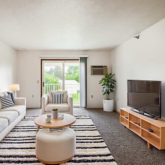 a living room with a white couch, a coffee table, and a television.
