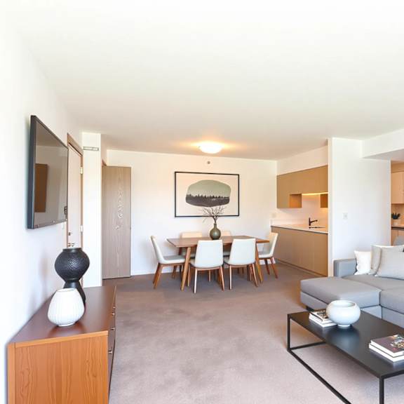 a living room with a grey couch, a coffee table, and a dining table with chairs.