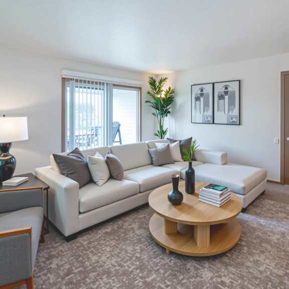 a living room with a white couch, a grey armchair, a wooden coffee table, and a grey rug.
