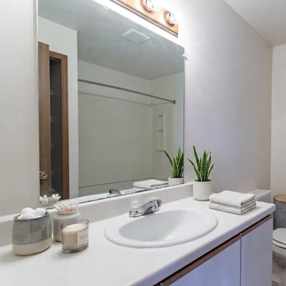 a white bathroom with a sink, toilet, and mirror.