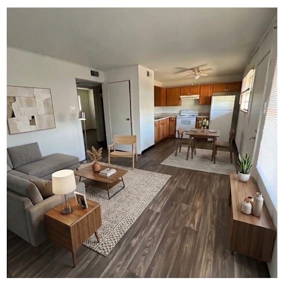a living room with a grey couch, a wooden coffee table, and a kitchen area in the background.