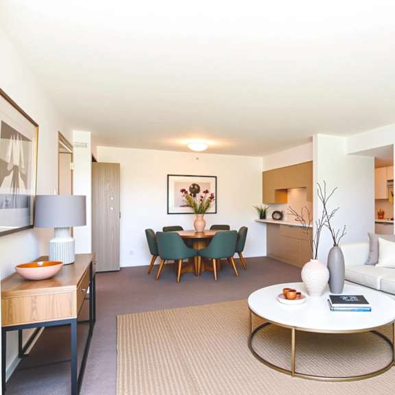a living room with a white couch, a coffee table, and a dining table with chairs.