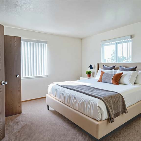 a bedroom with a bed, nightstand, and window.