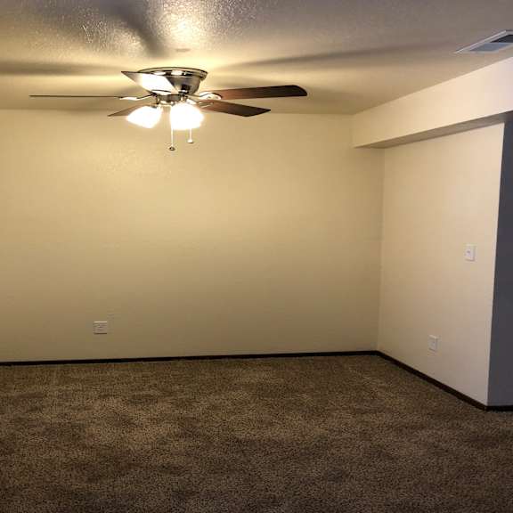 a room with a ceiling fan and a carpet