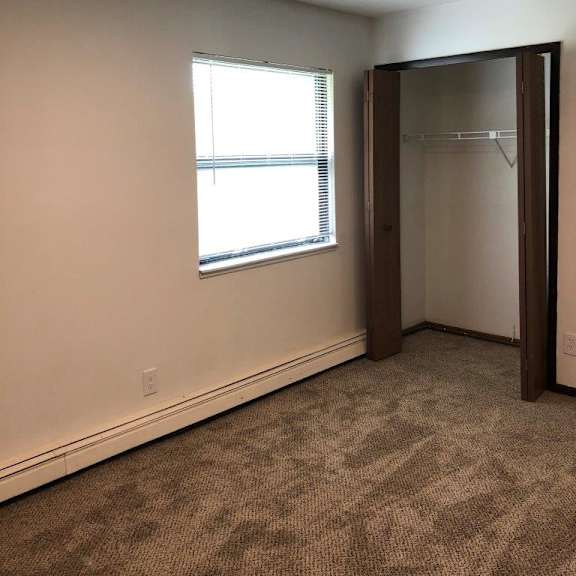 an empty room with a window and a closet