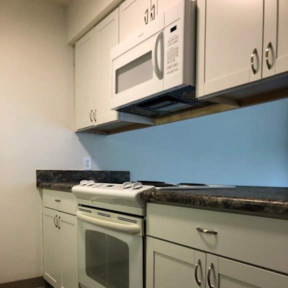 a kitchen with white cabinets and a white stove top oven