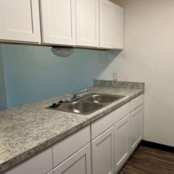 a kitchen with white cabinets and a sink and a refrigerator