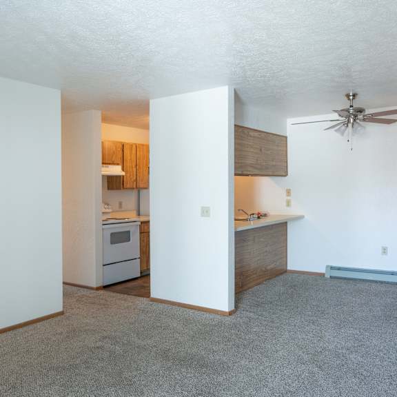 an empty living room and kitchen with a ceiling fan