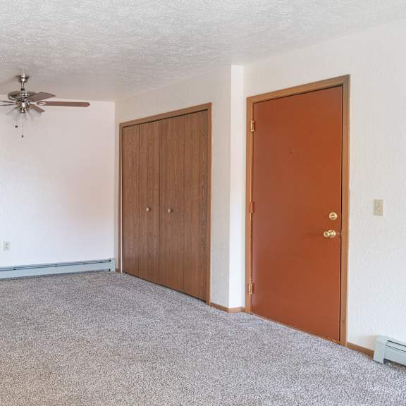 an empty room with a ceiling fan and two doors