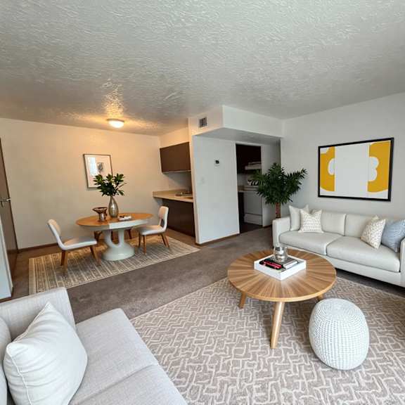 a living room with a white couch, a wooden coffee table, and a painting on the wall.