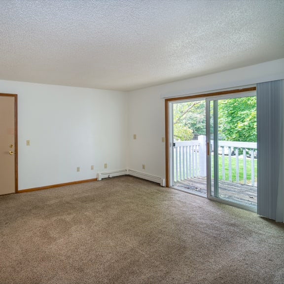 an empty living room with a sliding glass door to a patio