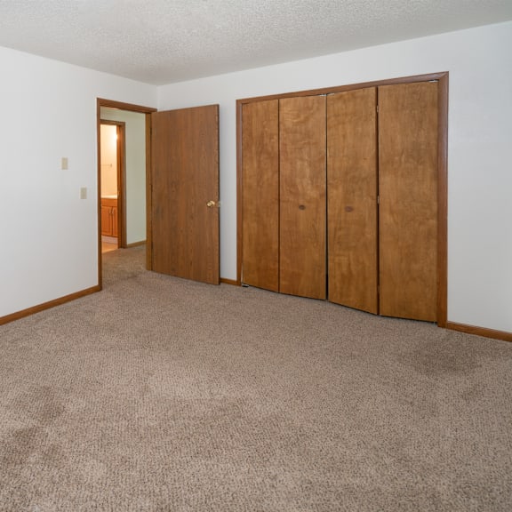 an empty living room with carpet and two wooden doors
