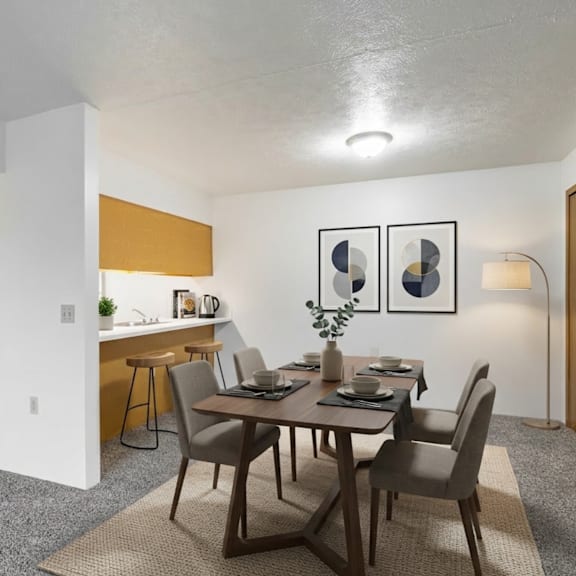a dining room with a table set for two and a kitchen area in the background.