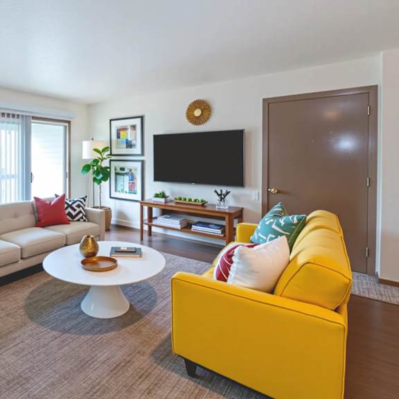 a living room with a yellow couch and a white coffee table.