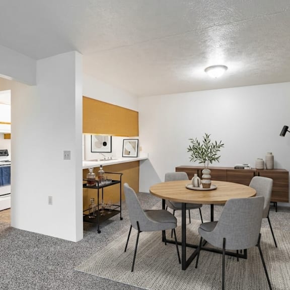 a dining room with a round table and grey chairs.