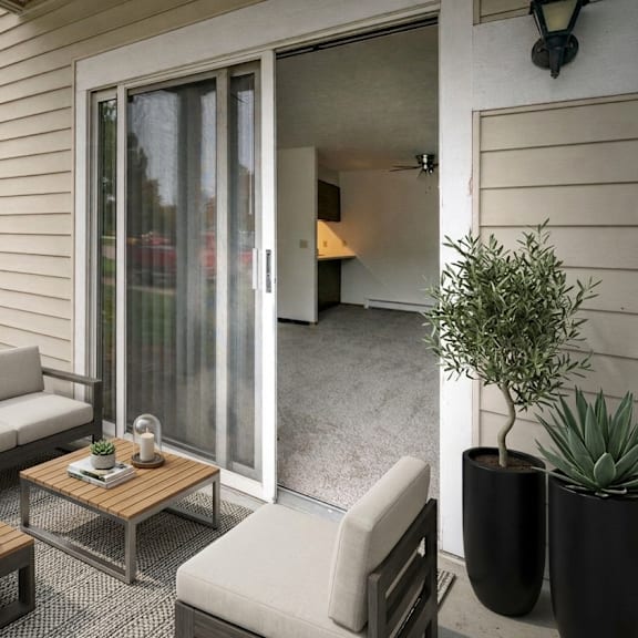 a patio with a grey couch, a wooden coffee table, and a potted plant.