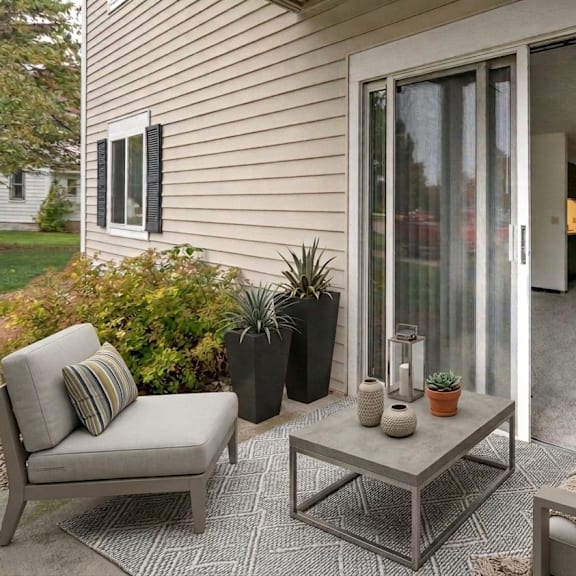 a patio with a grey couch, a grey chair, a grey coffee table and a grey rug.