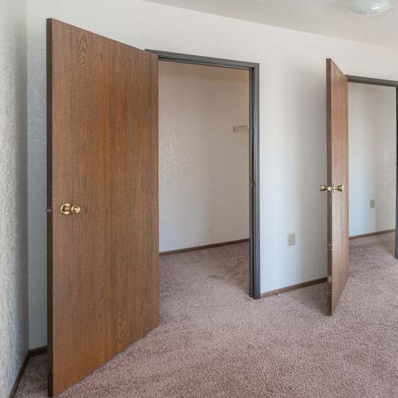 an empty bedroom with three doors and carpeting