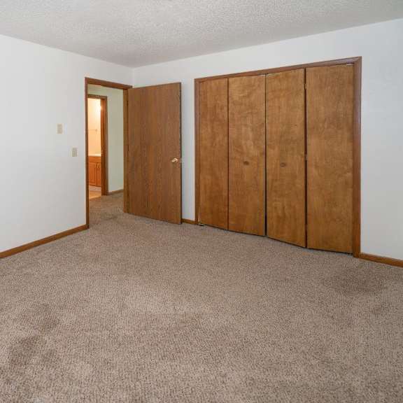 an empty living room with a carpeted floor and two closet doors