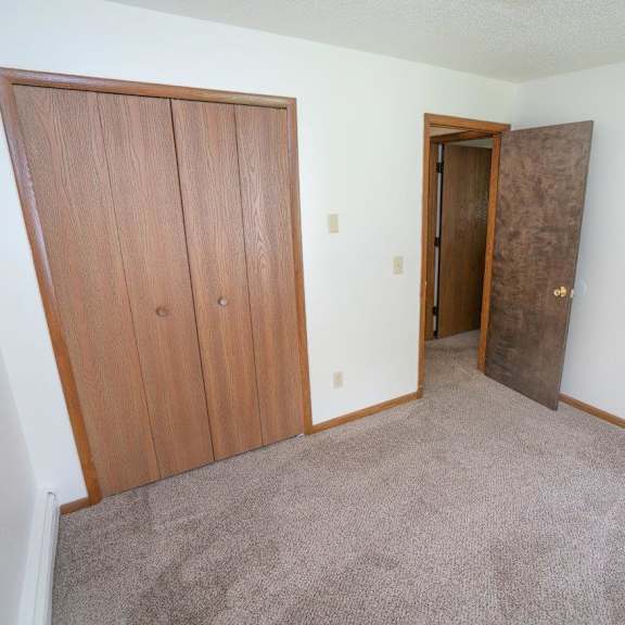 an empty room with two doors and a carpeted floor