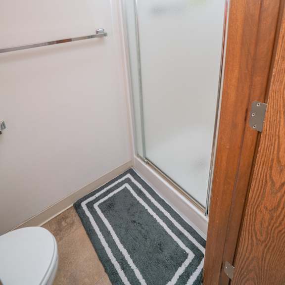 walk in showers with built in bench and glass enclosure at raleigh house apartments, mrd apartments, michigan, 48823