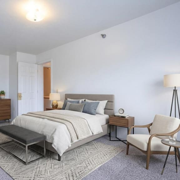 a bedroom with a large bed, a chair, and a nightstand.