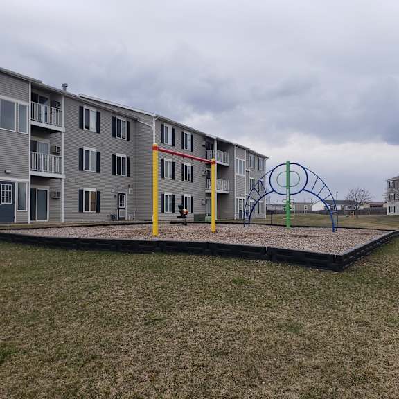 a playground with a swing set in front of apartment buildings.
