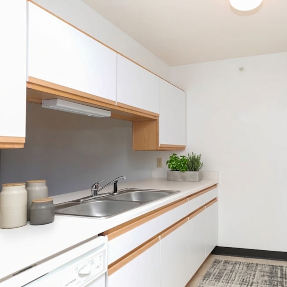 a small kitchen with white cabinets and a white fridge.