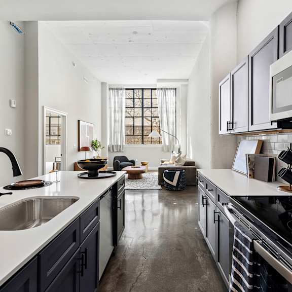 a kitchen with white counters and black appliances and a large window