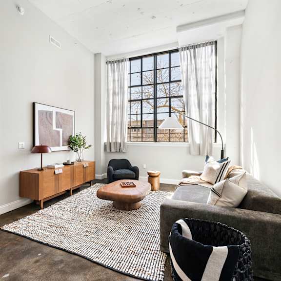 a living room with a gray couch and a rug and a window