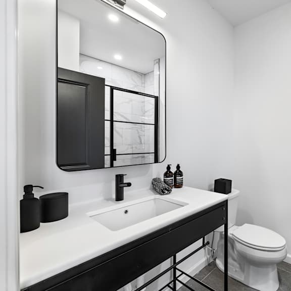 a bathroom with a toilet sink and mirror and a black door