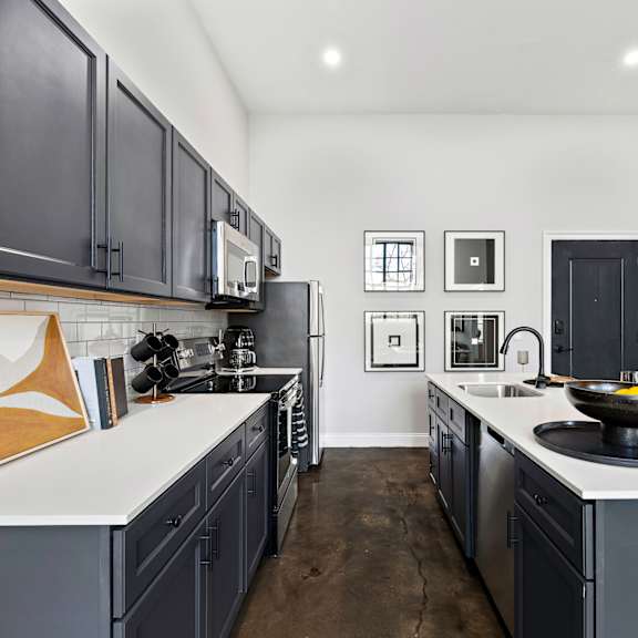 an open kitchen with black cabinets and white countertops and a large sink and counters