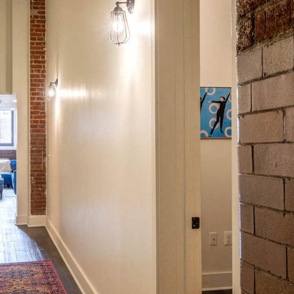 the hallway of a home with a brick wall and a carpet