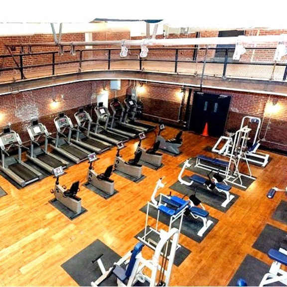 a gym with a bunch of exercise equipment on a wooden floor
