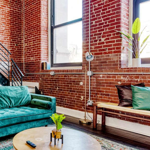 a living room with a green couch and a brick wall