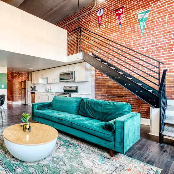 a living room with a turquoise couch and a table and a staircase