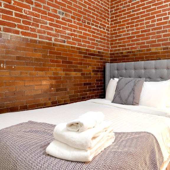 a bedroom with a bed and a brick wall