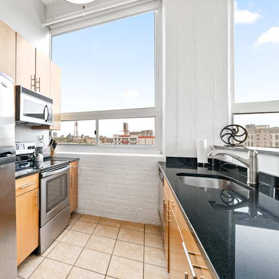 a kitchen with black countertops and stainless steel appliances and a large window