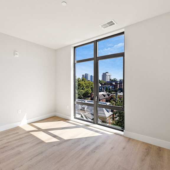 an empty living room with a large window and wooden floors