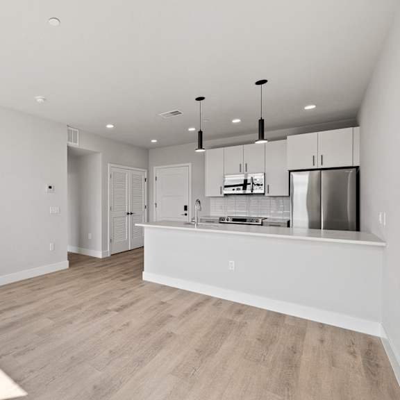 an open kitchen and living room with a large island and a refrigerator and microwave