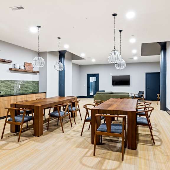 a communal dining room with tables and chairs and a kitchen with a tv