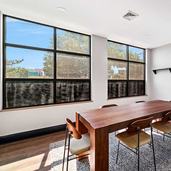 a dining room with a wooden table and chairs and large windows