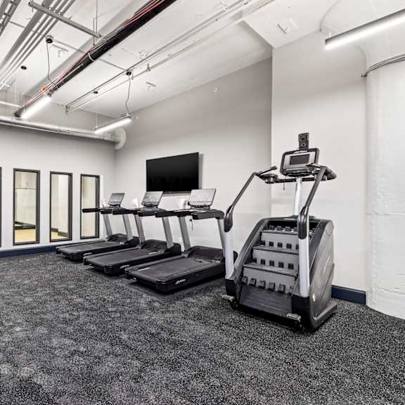 a gym with treadmills and weights in a room with windows