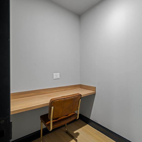 a desk in a corner of a room with a chair
