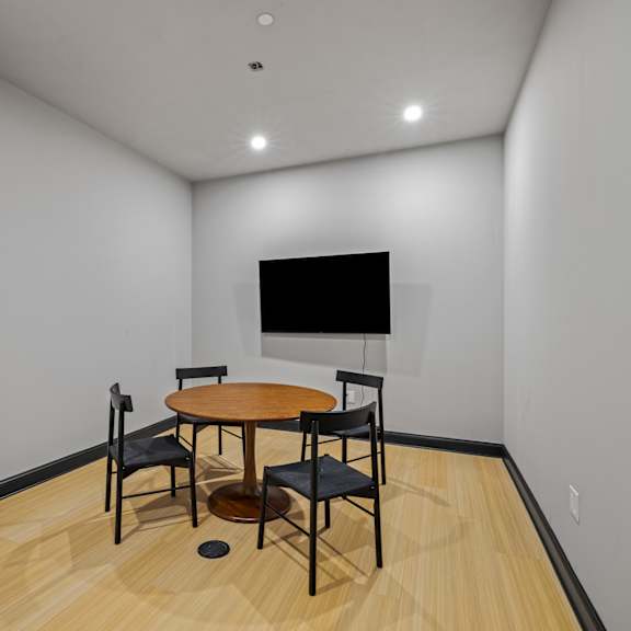 a room with a table and chairs and a television on the wall