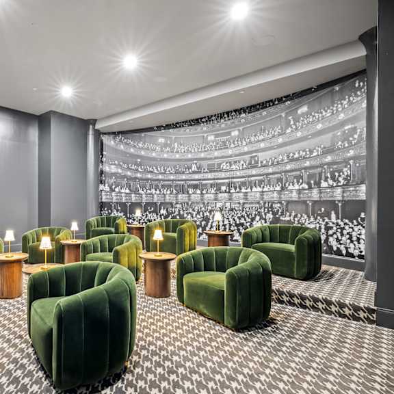 a large theater room with green chairs and a projector screen
