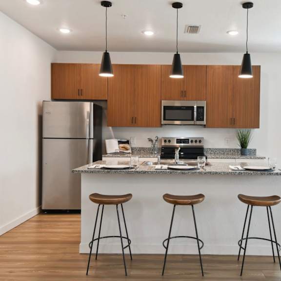 Thumbnail 2 of 4 a kitchen with a island and three bar stools in front of a kitchen counter at Gibson Oaks, Lakeland, 33809