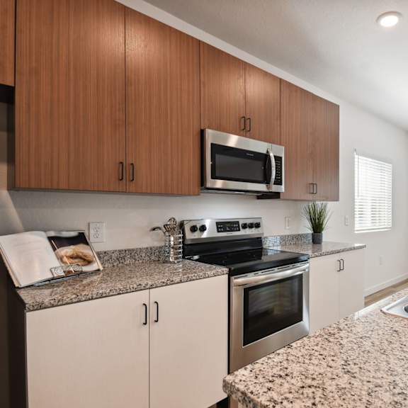 Thumbnail 3 of 4 a modern kitchen with granite counter tops and stainless steel appliances at Gibson Oaks, Lakeland, 33809