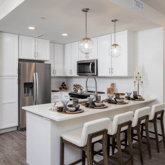 Thumbnail 2 of 6 A modern kitchen with a white island and dark wood floors at 2020 Providence in Huntsville, AL